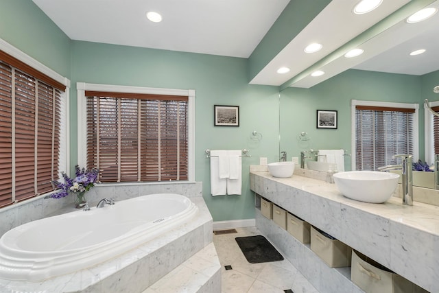 bathroom featuring tiled bath, vanity, and tile patterned flooring