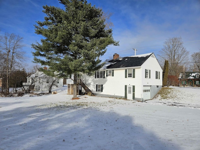 snow covered back of property featuring a garage