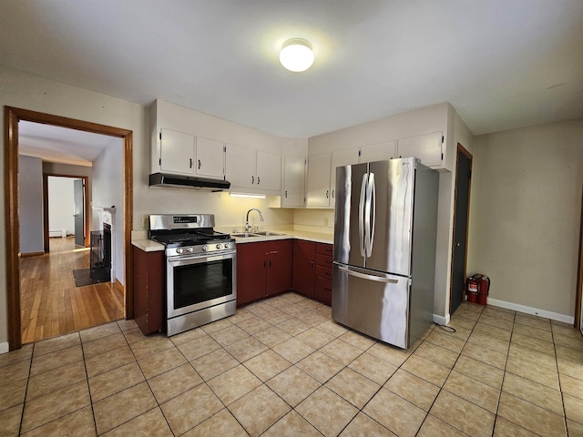 kitchen with light tile patterned floors, white cabinetry, stainless steel appliances, baseboard heating, and sink