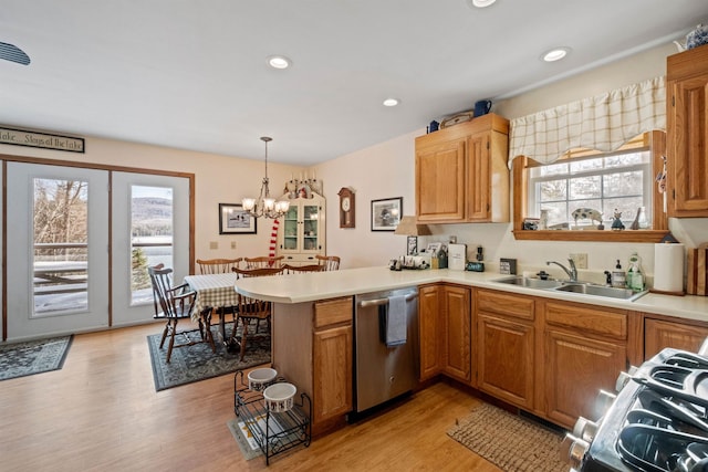 kitchen featuring stainless steel appliances, sink, hanging light fixtures, kitchen peninsula, and light hardwood / wood-style flooring