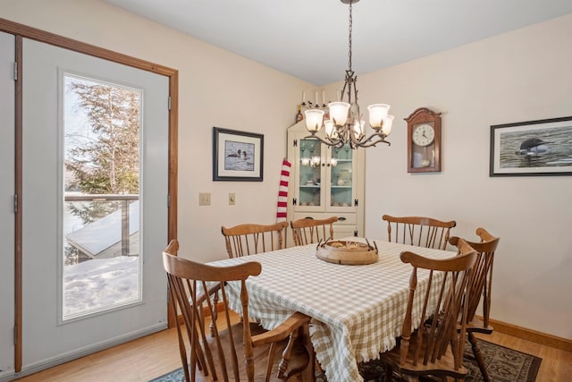 dining room with a healthy amount of sunlight, light wood-type flooring, and a chandelier