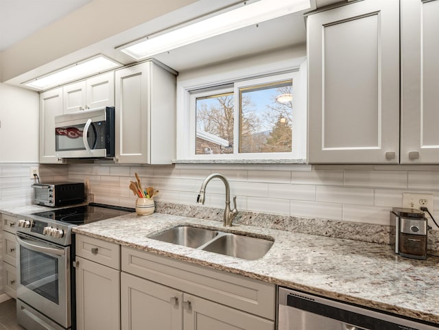 kitchen featuring light stone countertops, stainless steel appliances, backsplash, and sink