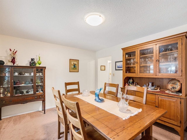 dining area featuring light carpet and a textured ceiling