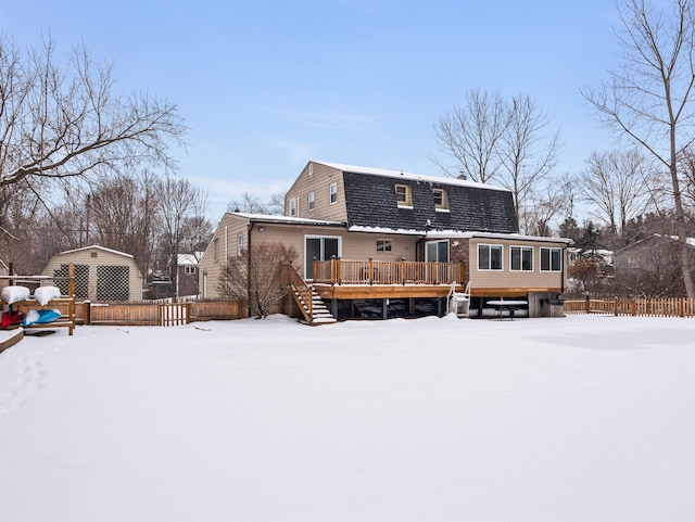 snow covered rear of property with a wooden deck