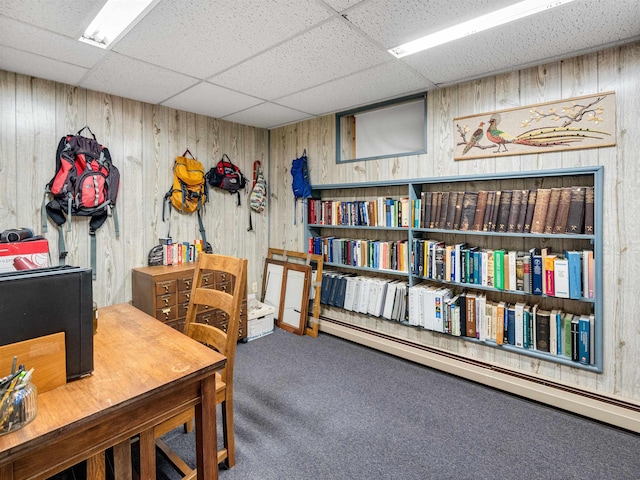 office featuring a paneled ceiling, wood walls, and carpet flooring