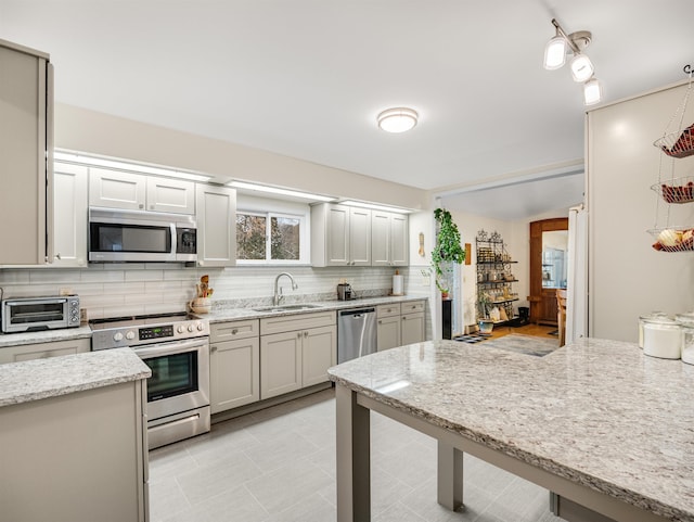 kitchen featuring light stone countertops, stainless steel appliances, decorative backsplash, and sink