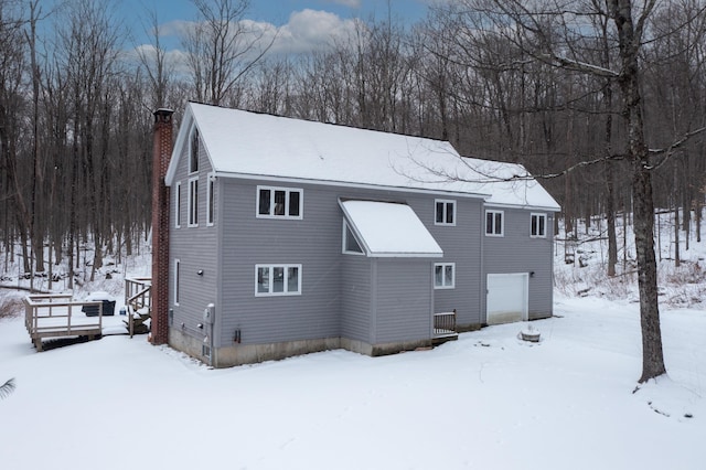 snow covered house featuring a garage