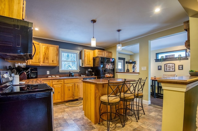 kitchen featuring a kitchen breakfast bar, hanging light fixtures, sink, black fridge, and range with electric cooktop