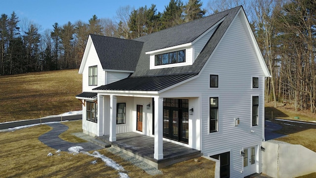 rear view of property featuring covered porch, french doors, and a lawn