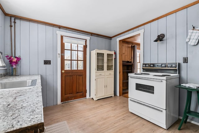 kitchen featuring wooden walls, sink, ornamental molding, electric range, and light hardwood / wood-style flooring