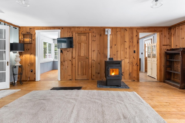 living room featuring wooden walls, a wood stove, and light hardwood / wood-style flooring