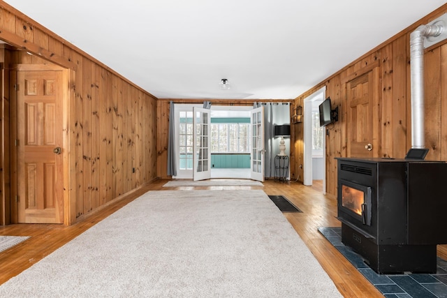 living room with wood walls, crown molding, a wood stove, and hardwood / wood-style floors