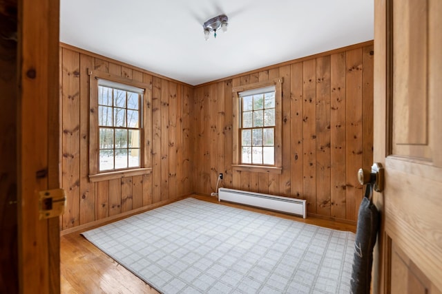 spare room featuring a baseboard heating unit, ornamental molding, and light hardwood / wood-style floors