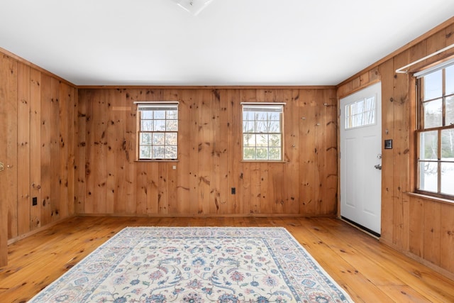 entrance foyer with wooden walls, crown molding, and light hardwood / wood-style flooring