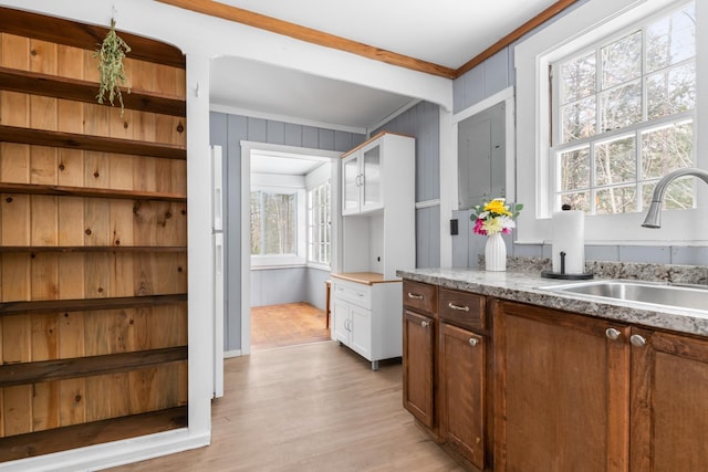 bar with white cabinetry, wooden walls, light wood-type flooring, ornamental molding, and sink