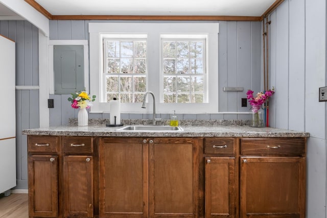 kitchen featuring light hardwood / wood-style floors, sink, ornamental molding, and wood walls