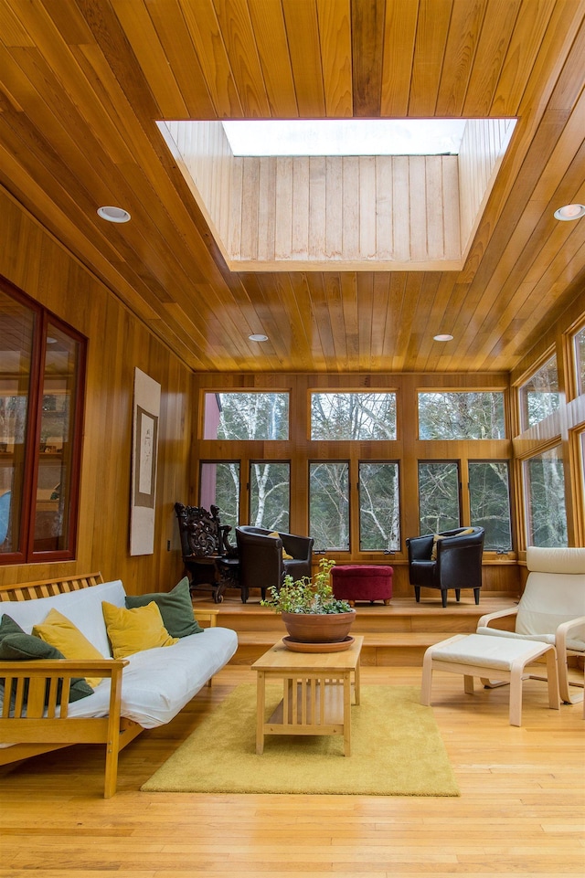 living room featuring a skylight, wood ceiling, hardwood / wood-style floors, and wooden walls