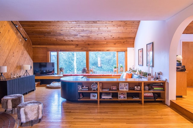 living room with vaulted ceiling, wood-type flooring, and wood walls