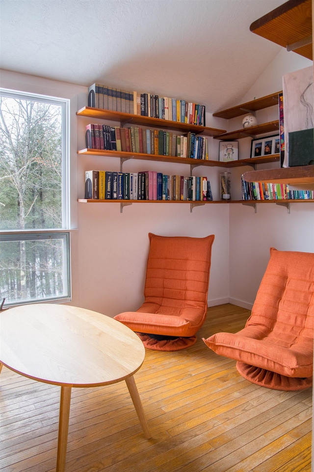 sitting room with hardwood / wood-style floors and vaulted ceiling