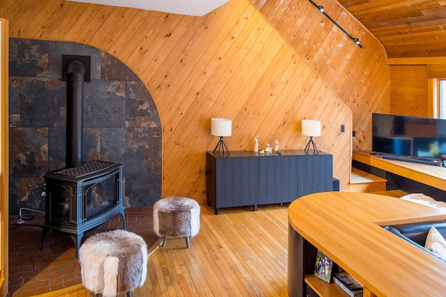 living room featuring vaulted ceiling, wood ceiling, wood walls, and a wood stove