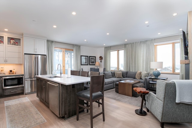 kitchen with white cabinets, appliances with stainless steel finishes, tasteful backsplash, sink, and a kitchen island with sink