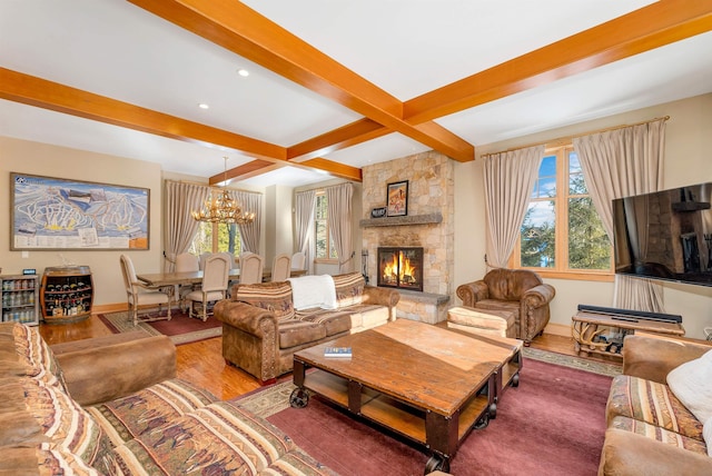 living room featuring hardwood / wood-style floors, beam ceiling, coffered ceiling, a stone fireplace, and a chandelier