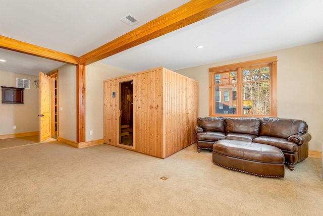 carpeted living room featuring beam ceiling