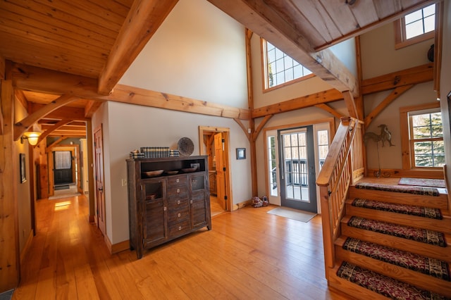 foyer with beam ceiling, light wood-type flooring, wood ceiling, and a high ceiling