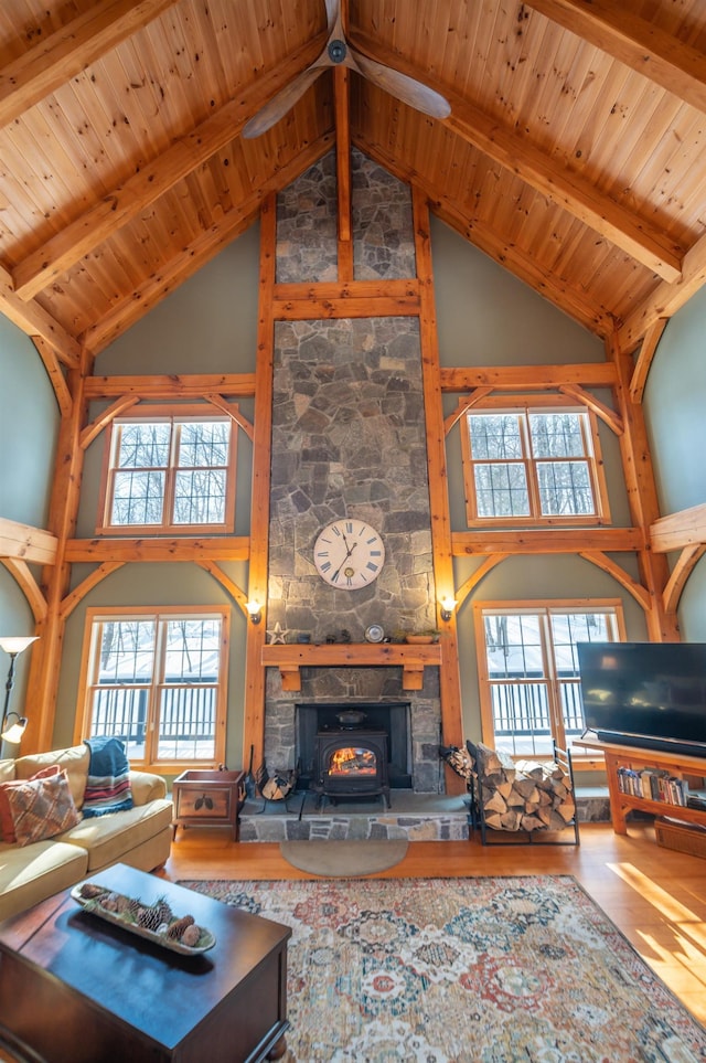 living room featuring high vaulted ceiling, a wood stove, wood-type flooring, and beamed ceiling