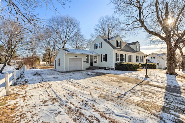 snow covered back of property featuring a garage