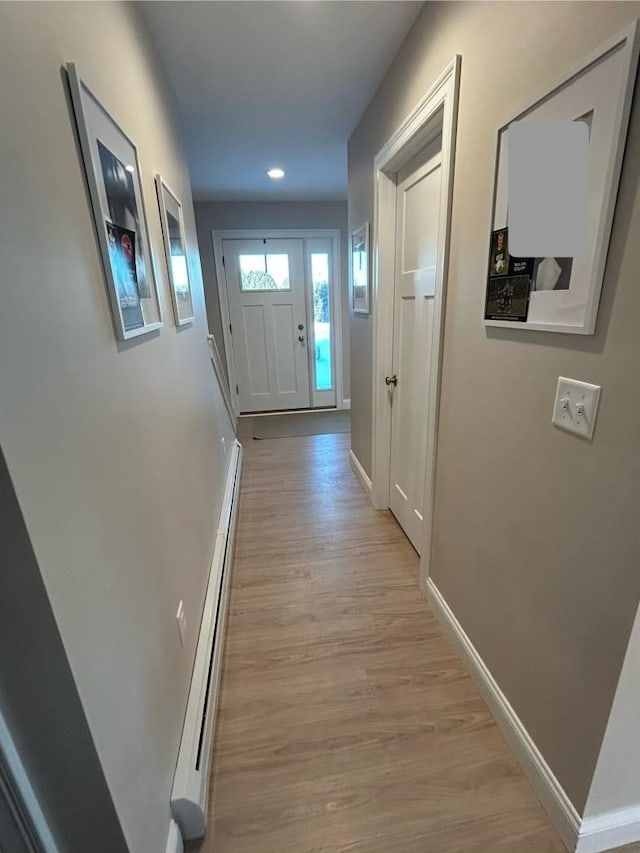 doorway with light wood-type flooring and a baseboard heating unit