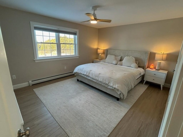 bedroom with ceiling fan, wood-type flooring, and a baseboard heating unit