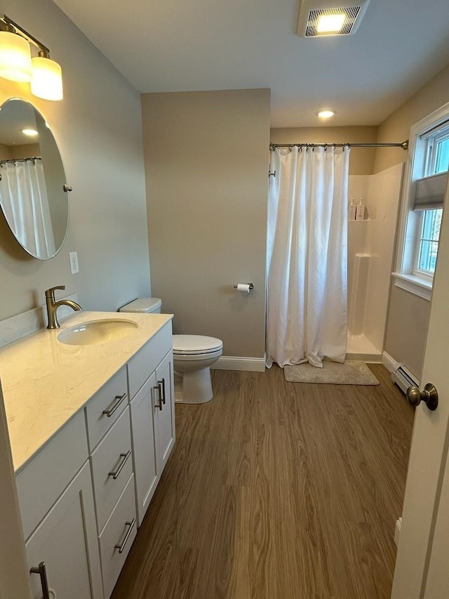 bathroom with toilet, vanity, a baseboard heating unit, hardwood / wood-style flooring, and curtained shower