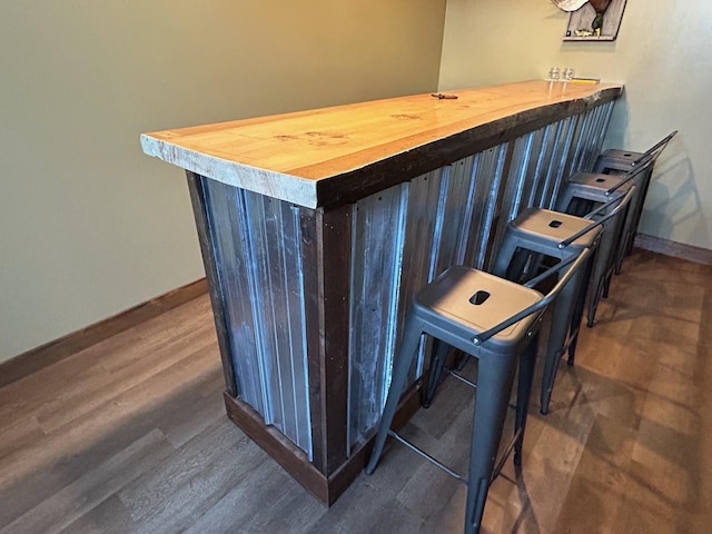 bar with butcher block countertops and dark hardwood / wood-style flooring