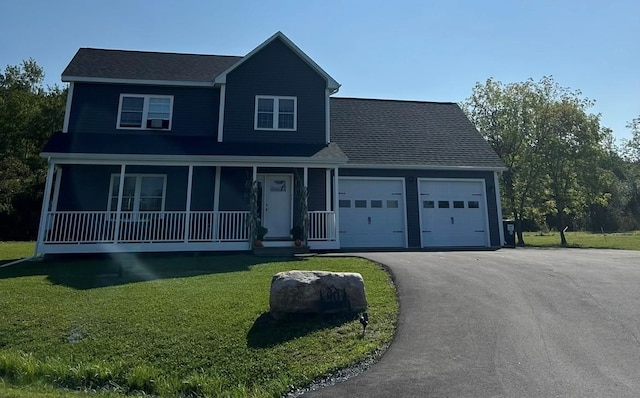 view of front of property featuring covered porch, a front lawn, and a garage