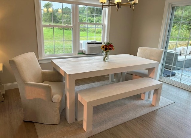 dining area with hardwood / wood-style floors, cooling unit, and an inviting chandelier