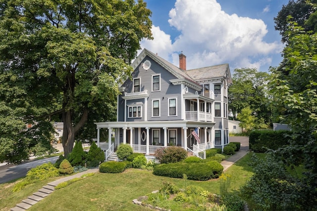 victorian house with a front lawn and a porch