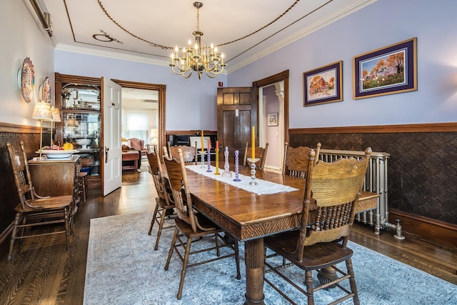 dining area with dark hardwood / wood-style flooring, ornamental molding, and a notable chandelier