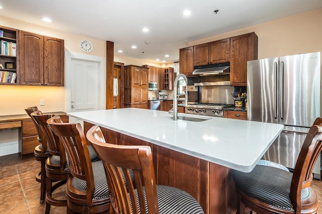 kitchen with appliances with stainless steel finishes, a kitchen bar, and a kitchen island with sink