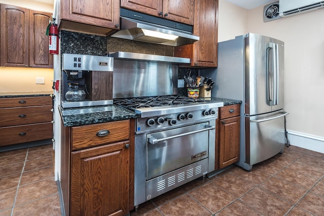 kitchen featuring tasteful backsplash, a wall mounted AC, dark stone countertops, dark tile patterned floors, and stainless steel appliances