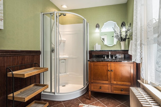 bathroom featuring tile patterned floors, walk in shower, radiator, and vanity