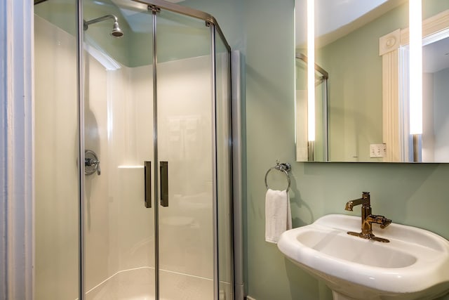 bathroom featuring a shower with shower door and sink