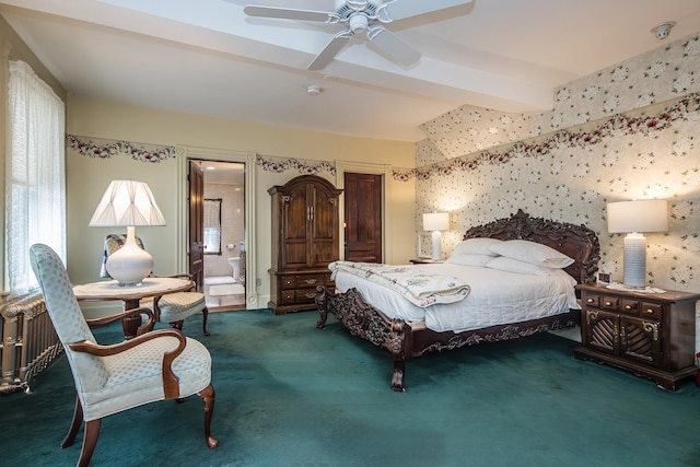 bedroom featuring ceiling fan, beam ceiling, dark carpet, and ensuite bath