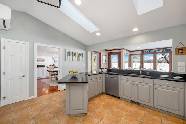 kitchen featuring vaulted ceiling with skylight, dishwasher, kitchen peninsula, and gray cabinetry