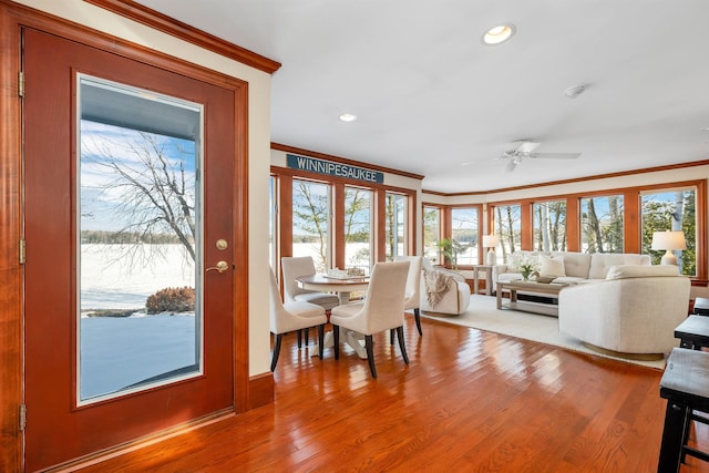 dining room with ceiling fan, ornamental molding, a water view, and hardwood / wood-style flooring