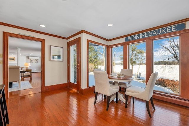 dining area featuring hardwood / wood-style floors, crown molding, and ornate columns