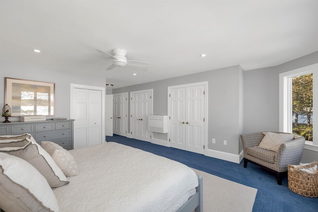 bedroom with ceiling fan, multiple windows, dark colored carpet, and multiple closets