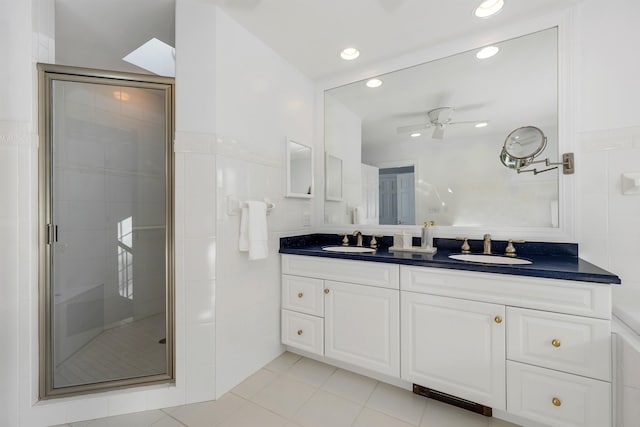 bathroom featuring a shower with shower door, ceiling fan, tile patterned flooring, tile walls, and vanity