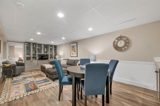 dining room with built in shelves, wood-type flooring, and a drop ceiling