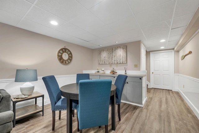 dining area featuring light wood-type flooring and a drop ceiling